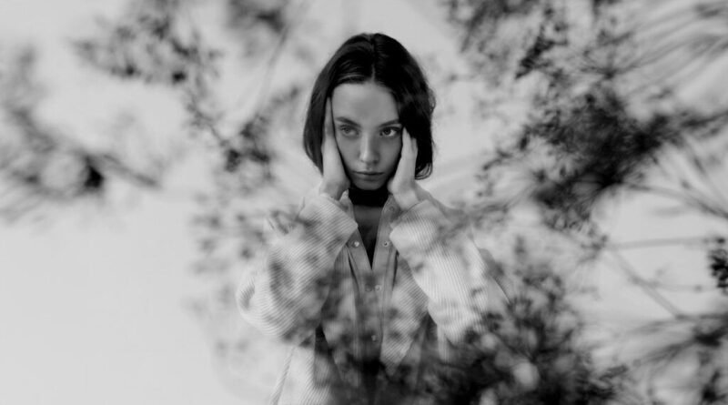 black and white photo of a young woman holding her temples